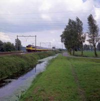 Gezicht op de Oud Wulfseweg tussen Utrecht en Houten, met een intercity op de spoorlijn Utrecht-'s-Hertogenbosch in mei - juni 1997. Naar een foto van Victor Lansink. Bron: Het Utrechts Archief, catalogusnummer: 852435.