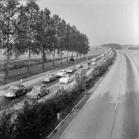 Afbeelding van een file op de Rijksweg 12 bij Utrecht, gezien vanaf het viaduct in de Houtenseweg bij De Koppel in het voorjaar of de zomer van 1962. Bron: Het Utrechts Archief, catalogusnummer: 125633.