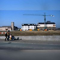 Foto uit 1984 met op de achtergrond een kantoorgebouw in aanbouw aan de Randhoeve met op de voorgrond twee jonge ouders met kind lopend op het Onderdoor. Achter hun moest het gemeentehuis nog gebouwd worden. Bron: Regionaal Archief Zuid-Utrecht (RAZU), 353.