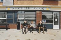 Mensen op een bankje voor Apotheek Loerik in de Loerikerstee aan het Hollandsspoor in 2001. Bron: Regionaal Archief Zuid-Utrecht (RAZU), 353, 45541, 35.