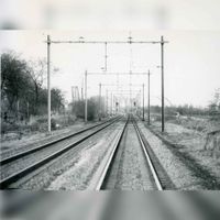 Gedeelte van de spoorlijn gezien vanaf de overgang van de Jonkheer Ramweg in noordelijke richting. Op de achtergrond links de spoorbrug over het Amsterdam-Rijnkanaal en rechts de verkeersbrug over het kanaal in 1990-1991. Bron: Regionaal Archief Zuid-Utrecht (RAZU), 353.