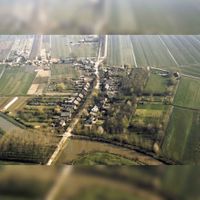 Luchtfoto van het dorp Tull vanuit het zuiden. Onderaan de foto het Inundatiekanaal, in het midden de Lange Uitweg met rechts de Achterdijk en links de Waalseweg in ca. 1990. Bron: RAZU, 353.