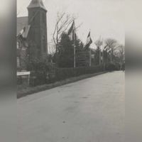 De Beusichemseweg met links de rooms-katholieke kerk. Vlaggen langs de weg en een grote groep mensen wachtend op de aankomt van de nieuwe pastoor in 1959. Bron: RAZU, 353.