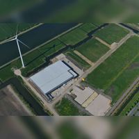 Luchtfoto gezien vanuit het noordoosten met links de windmolen 'De Windacus' met ernaast een bedrijfspand aan de Oude Hoon 2 in 2017. Foto: Slagboom en Peeters Luchtfotografie B.V..