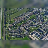 Luchtfoto gezien vanuit het noorden in 2019 met links de Staatslijn H (Utrecht-'s-Hertogenbosch) in het dorp te Schalkwijk met diagonaal de Wickenburghselaan met de straten De Groes en de Biesterlaan. Foto: Slagboom en Peeters Luchtfotografie B.V..