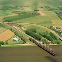 Luchtfoto van de Schalkwijkseweg en de spoorbrug over het Amsterdam-Rijnkanaal te Houten met links zwembad De Trip, uit het zuidwesten. Op de achtergrond de Hoogdijk op 15 juni 1996. Bron: Het Utrechts Archief, catalogusnummer: 85647.