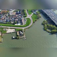 Luchtfoto gezien vanuit het noorden op de Oostdijk van Oud-IJsselmonde met de rivier de Nieuwe Maas, met rechtsboven de rijksweg A16. Staande op de oostelijke oever van het eiland Van Brienenoord met daarbij de Van Brienenoordbrug in 2019. Foto: Slagboom en Peeters Luchtfotografie B.V..
